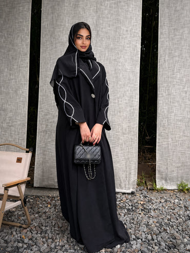Full-length front view of a black open abaya and matching hijab with white embroidery on the lapels and sleeves. 2