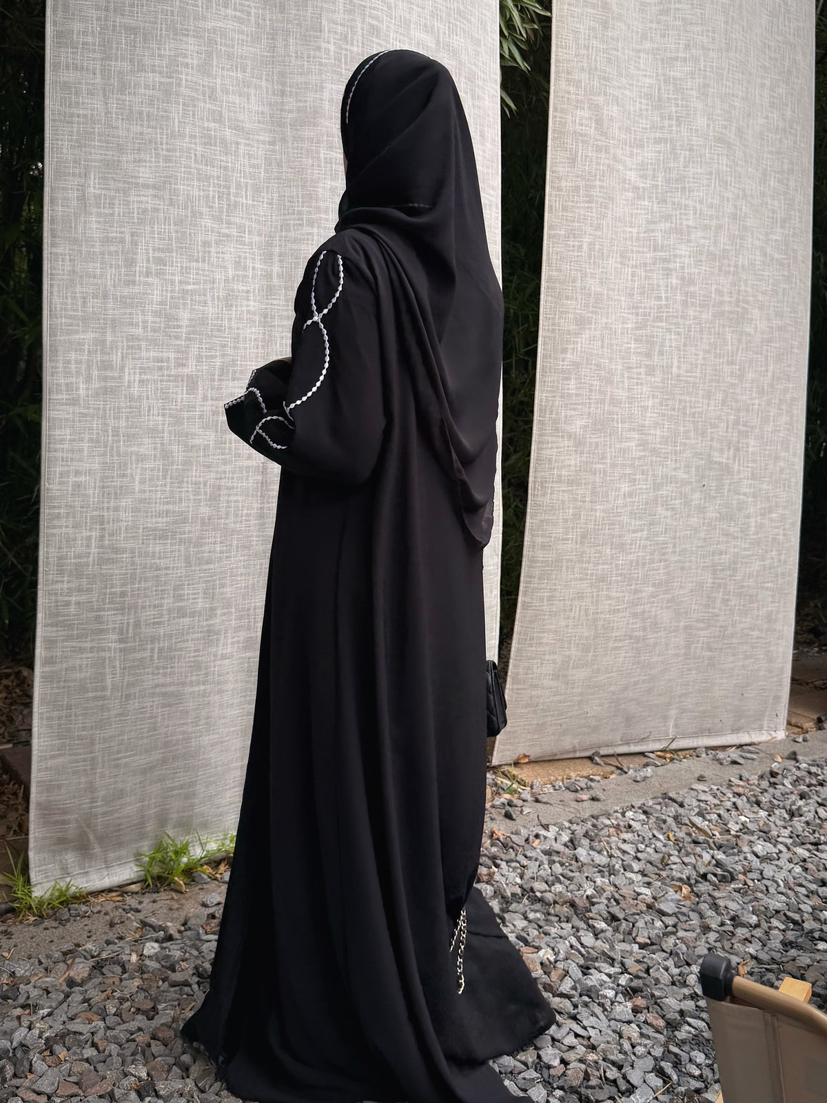 Back view of the black abaya and draped matching hijab, showing the full-length silhouette.