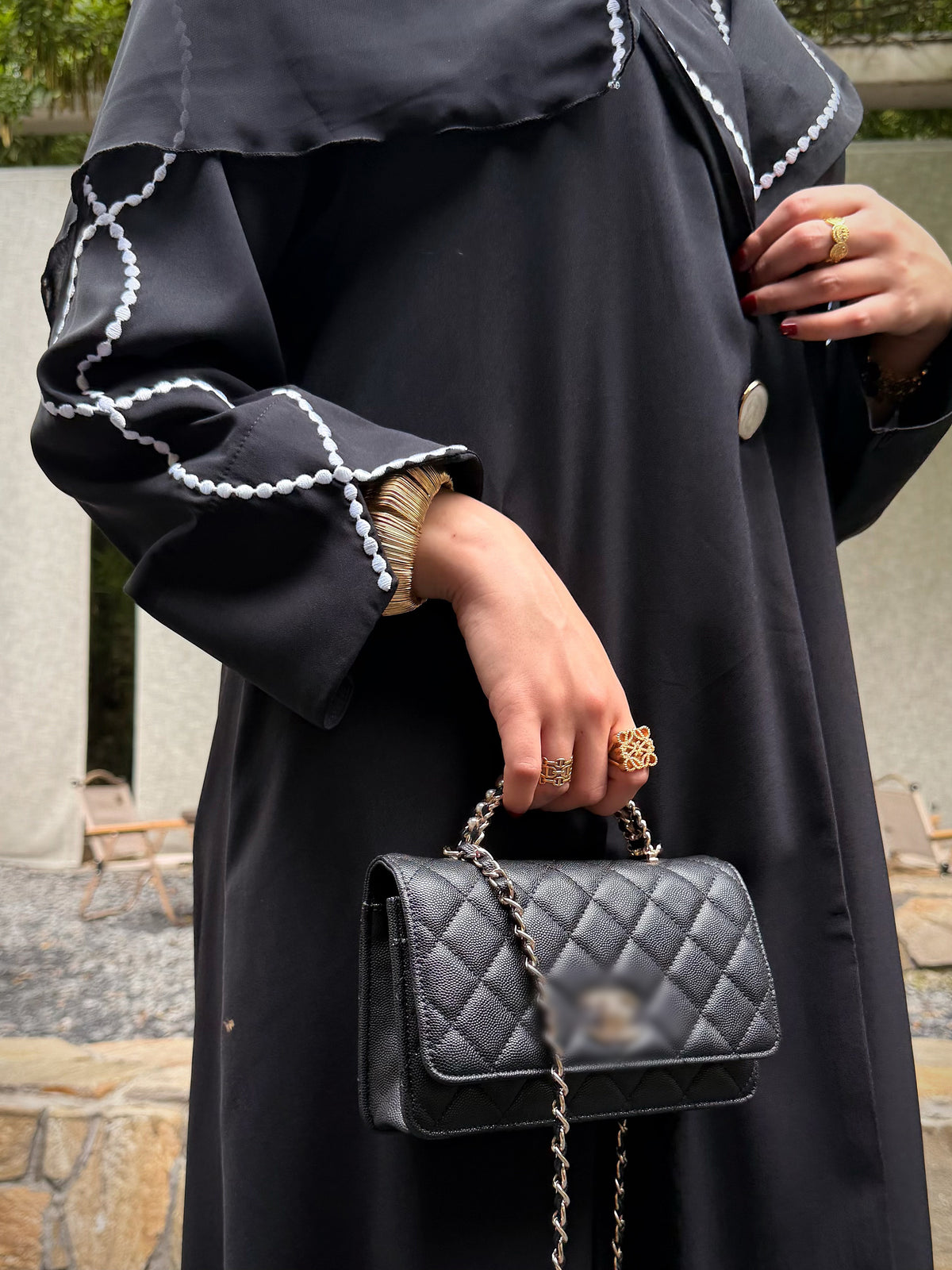 Close-up of the black abaya cuff with white embroidered loops and a flared opening.