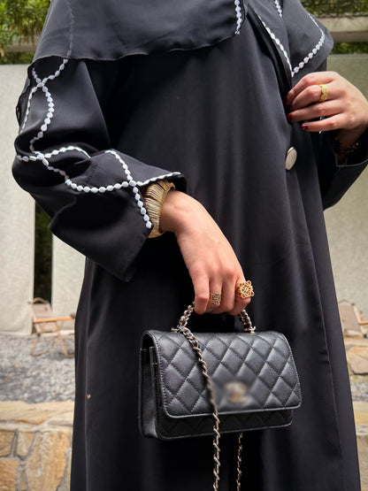 Close-up of the black abaya cuff with white embroidered loops and a flared opening. 7