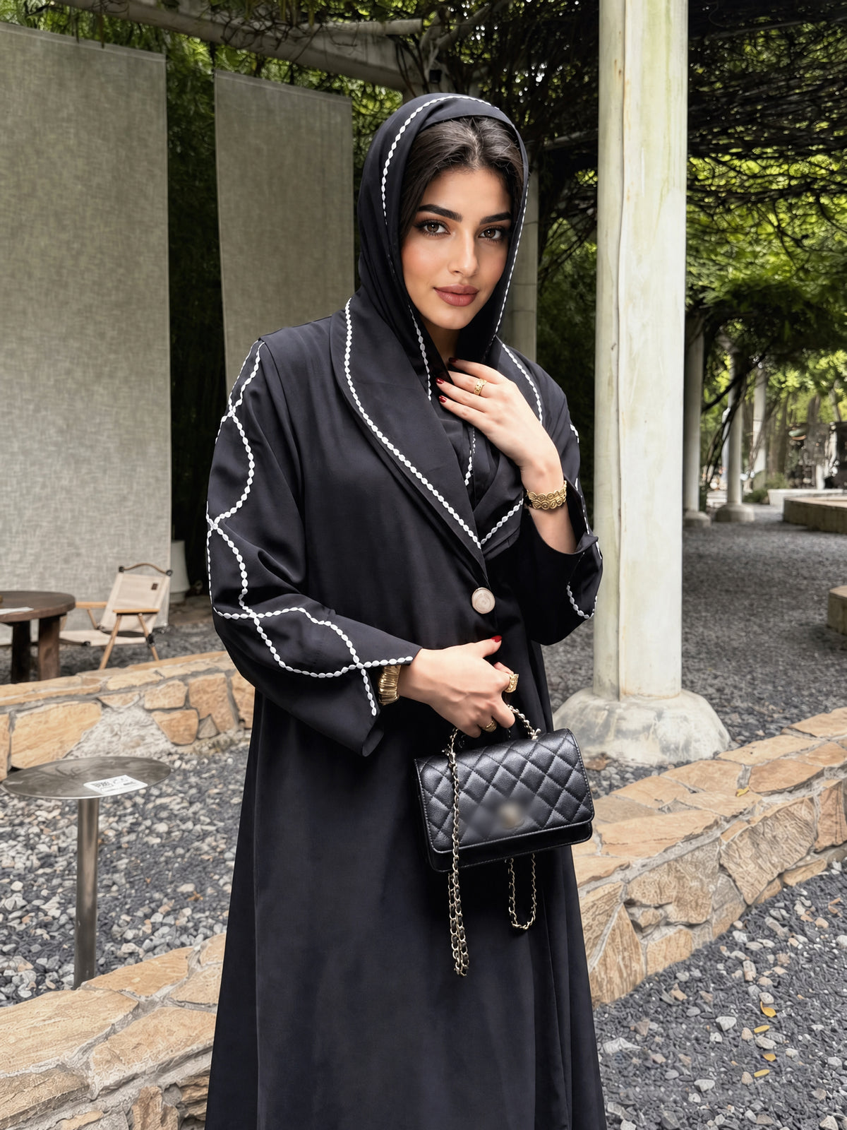 Closer front view of the black abaya, highlighting white embroidery on the lapels and matching hijab edge.