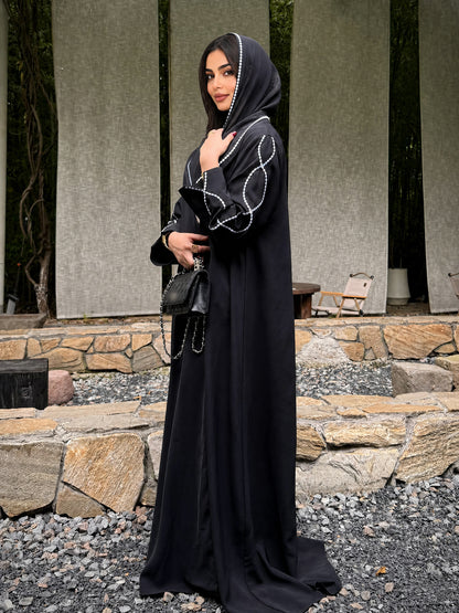 Full-length side view of the black embroidered abaya and matching hijab with white edging. 6