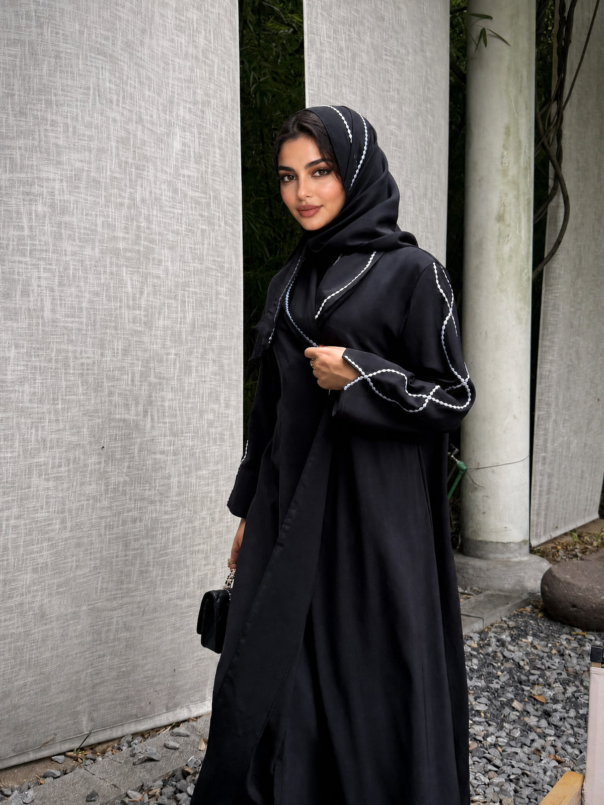 Three-quarter view of the black abaya with white loop embroidery on the sleeve.
